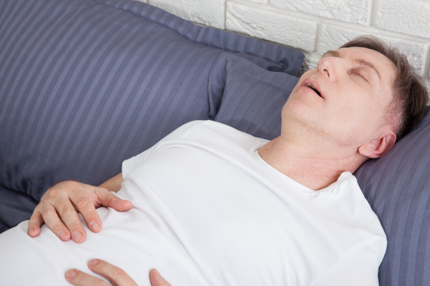 Man snoring because of sleep apnea lying in the bed. Premium Photo